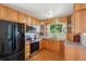 Well-lit kitchen featuring wood cabinets, stainless steel appliances, and a window overlooking the backyard at 11349 Downing Dr, Northglenn, CO 80233