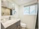 Bathroom featuring a marbled vanity, matching mirror, and tiled shower behind the toilet at 7010 W 44Th Ave, Wheat Ridge, CO 80033