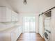 Bright laundry room with white cabinetry, sliding door, and stacked washer and dryer at 7010 W 44Th Ave, Wheat Ridge, CO 80033