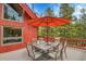 Outdoor dining area on back deck with umbrella and overlooks lush evergreens and mountainous views at 387 Pine Dr, Idaho Springs, CO 80452
