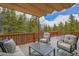 Outdoor deck with comfortable seating, side table, and partial awning, perfect for enjoying the forested surroundings at 387 Pine Dr, Idaho Springs, CO 80452