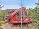Exterior of chalet-style house with multiple decks, red wood siding, large windows, and mountain views at 387 Pine Dr, Idaho Springs, CO 80452
