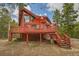 Exterior of a red chalet-style house with a deck, surrounded by tall trees and a blue sky at 387 Pine Dr, Idaho Springs, CO 80452