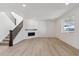 Spacious living room featuring sleek fireplace, staircase, and light wood flooring at 660 Split Rock Dr, Erie, CO 80516