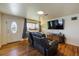 Bright living room with hardwood floors, a flat screen TV, and front entry access at 6860 Krameria St, Commerce City, CO 80022