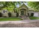 Home's exterior boasts a well-manicured lawn, complemented by mature trees and a charming front porch at 1235 S Balsam St, Lakewood, CO 80232
