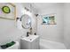 Modern bathroom with gray tile, a large round mirror, and natural light from the window at 2996 S Sheridan Blvd, Denver, CO 80227
