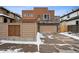 Contemporary home featuring a stone accent wall, a balcony, and a spacious driveway covered in snow at 467 Harrison St, Denver, CO 80206