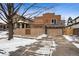 Contemporary home featuring a stone accent wall, a balcony, and a spacious driveway covered in snow at 467 Harrison St, Denver, CO 80206