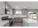 Modern kitchen featuring stainless steel appliances, gray cabinets, and a center island with stone countertops at 5957 N Orleans St, Aurora, CO 80019