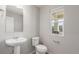 Bright powder room with pedestal sink, toilet, and a window bringing in natural light at 5957 N Orleans St, Aurora, CO 80019