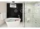 Contemporary bathroom showcasing a soaking tub, decorative chandelier, black marble accent wall, and glass-enclosed shower at 418 Steele St, Denver, CO 80206