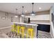 Bright kitchenette with yellow bar stools, stainless steel appliances, and blue pendant lights at 5072 Silver Hare Ln, Castle Rock, CO 80104
