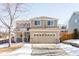 Two-story house with beige exterior, attached garage, and snowy landscape at 11002 Glacier Park Cir, Parker, CO 80138