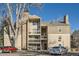 Multi-story condo building with beige siding, stone chimney, and balconies, with parking area at 4866 S Dudley St # 2, Littleton, CO 80123