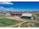 Aerial view showcasing a property with a barn, basketball court, and fenced-in yard at 55610 E 40Th Ave, Strasburg, CO 80136