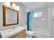 Well-lit bathroom with a modern vanity, mirror, and a shower with a blue curtain at 9759 Lane St, Thornton, CO 80260