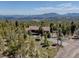 Stunning aerial view of a home surrounded by a lush forest with views of the mountains in the distance at 32091 Black Widow Dr, Conifer, CO 80433