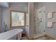 Bright bathroom showcasing a soaking tub beneath a window and a frameless glass shower at 32091 Black Widow Dr, Conifer, CO 80433