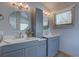Modern bathroom featuring dual vanities, round mirrors and stylish lighting fixtures with a window for natural light at 32091 Black Widow Dr, Conifer, CO 80433