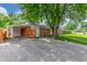 Brick home featuring an attached carport garage and large driveway with a mature shade tree providing curb appeal at 10784 Allendale Dr, Arvada, CO 80004