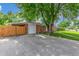 Brick home featuring an attached garage and large driveway with a mature shade tree providing curb appeal at 10784 Allendale Dr, Arvada, CO 80004