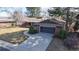 View of the brick home featuring a two-car garage, with beautiful landscaping and mature trees at 178 E 11Th Ave, Broomfield, CO 80020