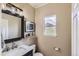 Stylish half bathroom with a marble countertop, decorative mirror, and natural light from the window at 11895 Hitching Post Ct, Parker, CO 80134