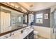 Bright bathroom featuring double vanity, marble countertops, and a glass enclosed shower at 11895 Hitching Post Ct, Parker, CO 80134