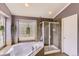 Primary bathroom with soaking tub, glass shower enclosure, tiled floors, and a privacy window at 11895 Hitching Post Ct, Parker, CO 80134