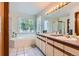 Bathroom featuring double sinks, a soaking tub by the window, and ample counter space at 7166 Newhall Dr, Highlands Ranch, CO 80130