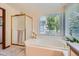 Bright bathroom with a soaking tub, separate shower with a glass door, and large window with natural light at 7166 Newhall Dr, Highlands Ranch, CO 80130