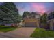 Charming two-story home showcasing a stone-accented garage, mature landscaping, and beautiful sunset at 7166 Newhall Dr, Highlands Ranch, CO 80130
