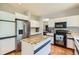 Well-lit kitchen with stainless steel refrigerator, an island with tile countertop, and ample cabinet space at 7166 Newhall Dr, Highlands Ranch, CO 80130