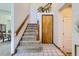 Entryway staircase with wood railing and neutral carpet leading to the upper level at 7166 Newhall Dr, Highlands Ranch, CO 80130