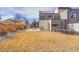 A modern home's backyard features a large, dry lawn, a trampoline, and a gray stone patio with outdoor furniture at 3910 Reed St, Wheat Ridge, CO 80033