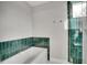 Bathroom with a stylish bathtub, accented by vibrant teal tiling and a glass-enclosed shower at 3910 Reed St, Wheat Ridge, CO 80033