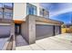 Modern home entrance featuring a gray brick exterior, spacious driveway, and a two-car garage at 3910 Reed St, Wheat Ridge, CO 80033