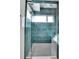Modern walk-in shower featuring vibrant teal tiles and a glass door, offering a luxurious experience at 3910 Reed St, Wheat Ridge, CO 80033