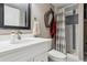 Bathroom with a white vanity, dark framed mirror, and a walk-in shower with patterned shower curtain at 7770 S Estes St, Littleton, CO 80128