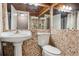 Bathroom with a pedestal sink, and rustic brown stone-style mosaic tile walls and mirrored back wall at 7770 S Estes St, Littleton, CO 80128