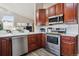 Modern kitchen with stainless steel appliances and wood cabinets next to living room at 7770 S Estes St, Littleton, CO 80128