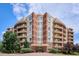 Beautiful condo building featuring brick accents, private balconies, and lush landscaping at 4875 S Monaco St # 303, Denver, CO 80237