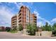 Exterior view of an elegant multi-story condo building with balconies, brick accents, and lush landscaping at 4875 S Monaco St # 303, Denver, CO 80237