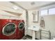 Bright laundry room features modern red washer and dryer with storage, sink, and space-saving shelving at 1640 Harrison St, Denver, CO 80206