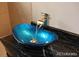 Stylish bathroom with a unique blue vessel sink and waterfall faucet on dark countertop at 15305 W 93Rd Ave, Arvada, CO 80007