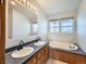 Bathroom with double vanity, bathtub, and wood cabinets at 6195 E 83Rd Pl, Commerce City, CO 80022