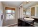 Bathroom vanity with a black countertop and a vessel sink complemented by a window with a woven shade at 6719 E Costilla Cir, Centennial, CO 80112