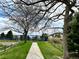 View of a walking path leading to the tennis court surrounded by trees and a split rail fence at 6719 E Costilla Cir, Centennial, CO 80112