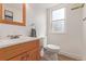 Bright bathroom features a wood framed mirror, wood vanity, and white toilet at 4808 S Ward Way, Morrison, CO 80465
